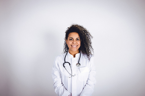 Latina female adult in a studio portrait photo wearing a medical coat showing positive facial expressions.