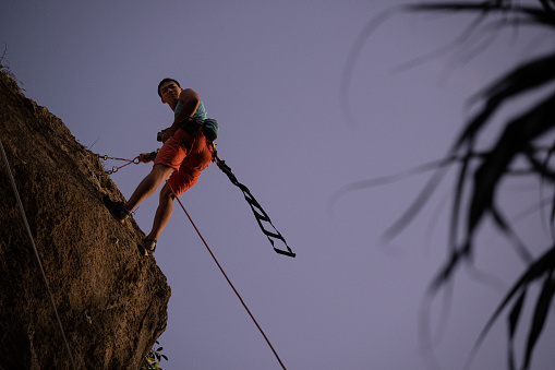 Climber ready to rappel off the wall, he’s taking a glance at the beautiful sunset.