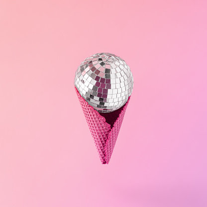 Minimal abstract Xmas decoration concept 90s with disco ball in red icecream cone on isolated gradient purple-pink background. Retro futuristic idea of New Year's Eve party. Vaporwave Christmas card.
