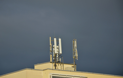 the flat roof of the residential apartment building is used as an antenna. dark sky before a storm. the lightning rod will protect the house and the expensive transmitter, signal amplifier, heat sink