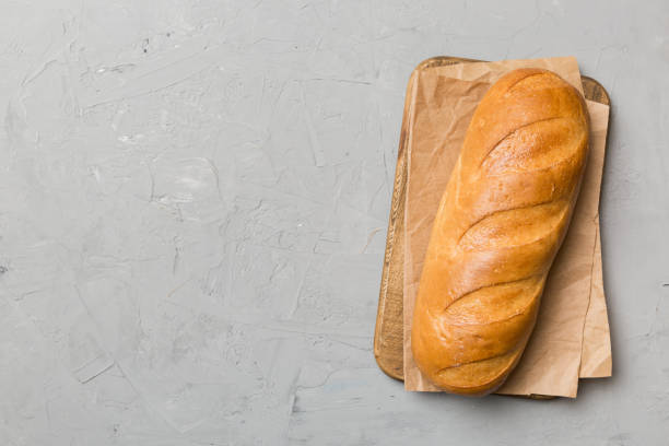 istock freshly baked bread with napkin on rustic table top view. Healthy white bread loaf isolated 1449382705