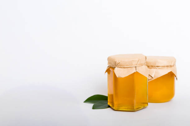 istock Honey in jar with leaves and honey dipper on colored background top view with copy text 1449382814