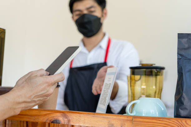 istock People scanning for pay for coffee and cake on cafe and collect point online by QR code. Mobile scanning online for pay on situation social distance . New normal. 1449382913