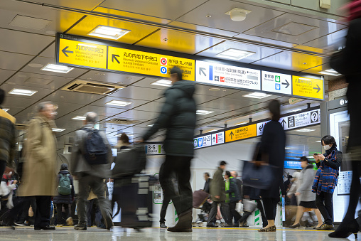 Tokyo, Japan - February 4, 2019: Direction signs and motion blurred passengers walking in JR Tokyo Station.