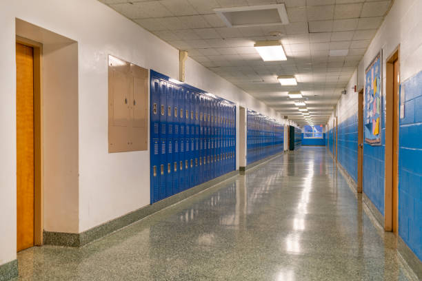 istock Typical, nondescript USA empty school hallway with royal blue metal lockers along both sides of the hallway. 1449383403