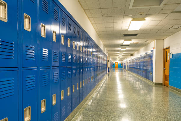 istock Typical, nondescript USA empty school hallway with royal blue metal lockers along both sides of the hallway. 1449383404