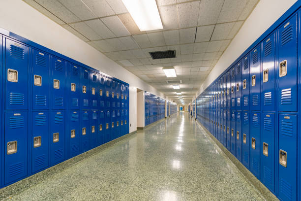 istock Typical, nondescript USA empty school hallway with royal blue metal lockers along both sides of the hallway. 1449383681