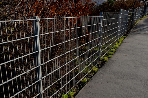 a solid wire fence encloses the garden. the welded wire meshes are strong and can be inserted between the prisms of the bars. the posts are concreted into the concrete slab fence, meadow, panel,