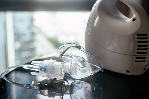 vernebler mit gesichtsmaske auf einem tisch im innenbereich - nebulizer stock-fotos und bilder