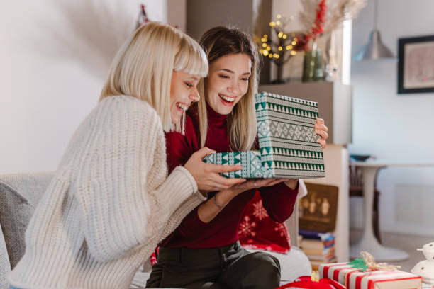 istock Young women opening Christmas present at home 1449384815