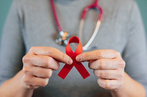 Female doctor holding a red ribbon, international day of protecting people from cancer