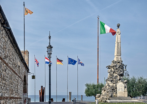 Flags and War monument adjacent to the Memorial Chapel in the Church of San Nicolo, Lazise, Italy.