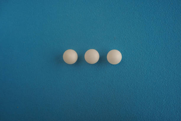 istock Three table tennis balls lie in a row on a blue background with a close-up view from above. Game for leisure. Sport equipment. International competition. Table tennis. Healthy lifestyle 1449389977