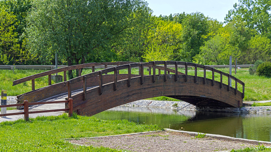 Wooden Arch Bridge Over Pond for Pedestrians in Park