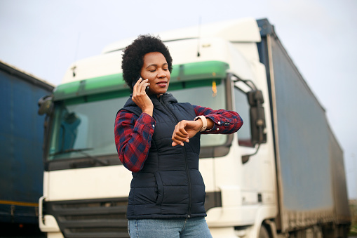 Mid adult female truck driver talking on a mobile phone. About 40 years old, African woman.
