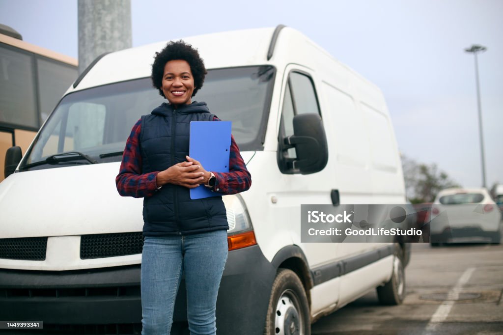 Van driver Mid adult female van driver. About 40 years old, African woman. Delivery Person Stock Photo