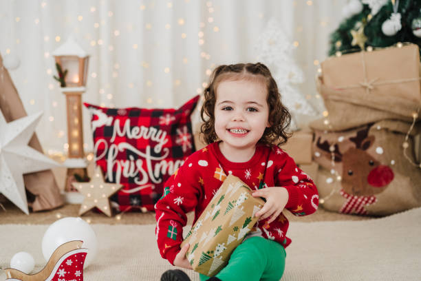 istock happy little girl at home holding presents during christmas time 1449397708