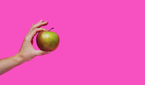istock Fruit apple in hand against pink background with copy space. 1449403334