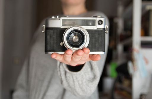 Woman with analog camera in a grey pullover