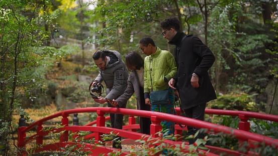 A group of multiracial friends are visiting a shrine and a Japanese garden enjoying taking photos.