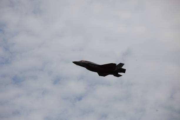 istock Side view of a fighter jet flying in blue cloudy sky 1449416018
