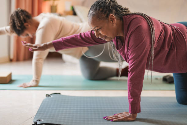 curvy african mother and daughter doing yoga exercise together at home - women yoga yoga class mature adult imagens e fotografias de stock