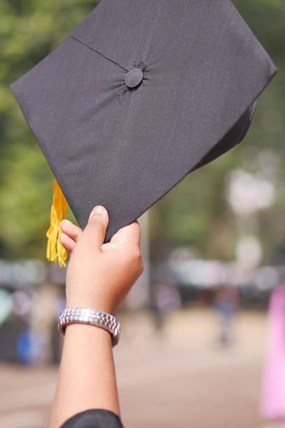 Student hold hats in hand during commencement success