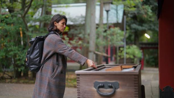 A female tourist is visiting a shrine and praying.