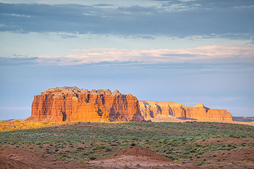 Hoodoo orange color rock sandstone unique formations of Goblin Valley State Park, Utah with desert plants at colorful sunset dusk or sunrise