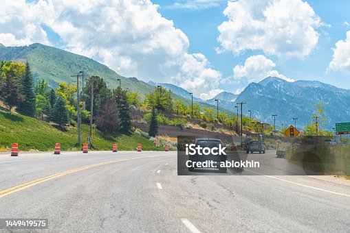 istock Cars driving on interstate highway road at Park City, Utah ski resort town with Wasatch mountains in summer background 1449419575