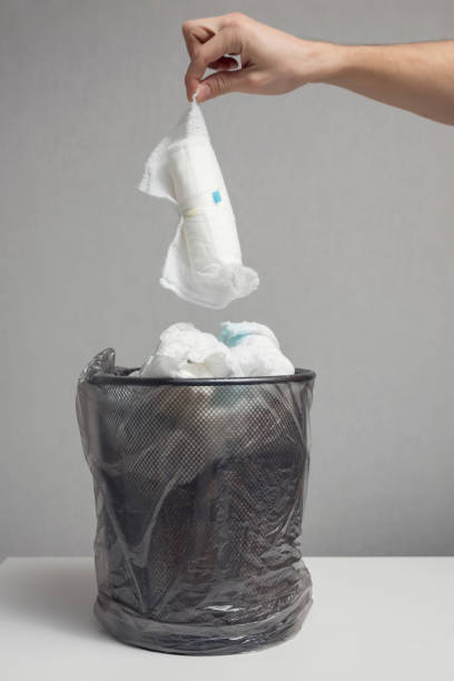 istock Person throws used diapers into loaded bin against grey wall 1449419685