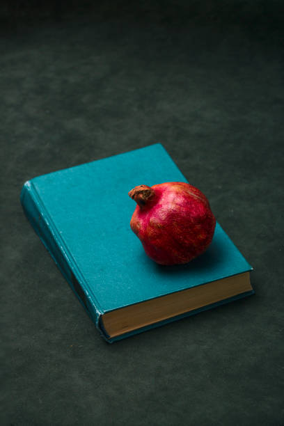 istock Red ripe pomegranate on the book, top view 1449420378