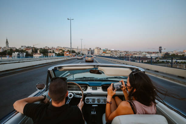 people riding in town in a vintage car People enjoying life, riding through the city in a vintage convertible car, having a relaxed weekend joyride. couple driving at night stock pictures, royalty-free photos & images