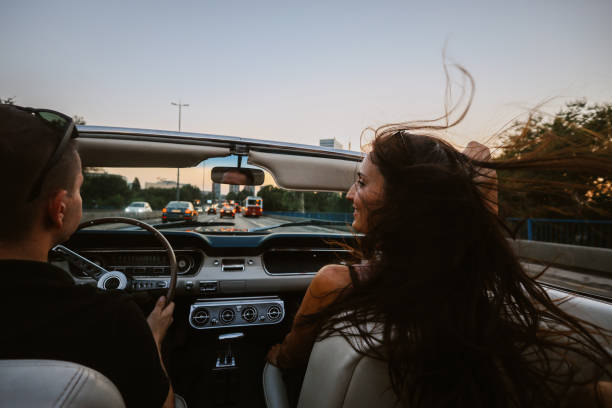 people riding in town in a vintage car People enjoying life, riding through the city in a vintage convertible car, having a relaxed weekend joyride. couple driving at night stock pictures, royalty-free photos & images