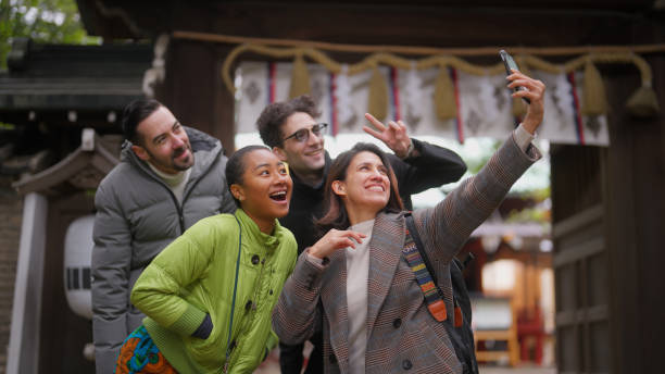 Group of multiracial friends visiting shrine and enjoying taking selfies