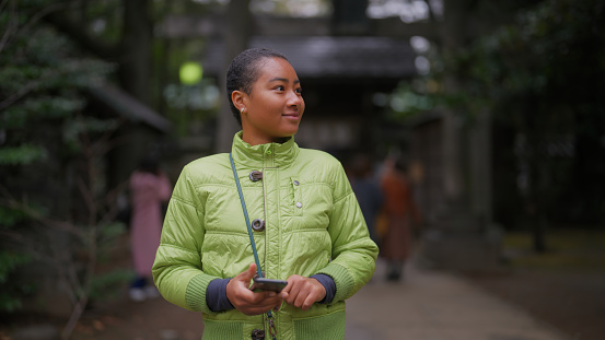 A female tourist is visiting a shrine and enjoying taking photos.
