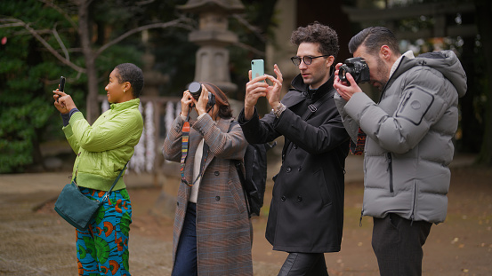 A group of multiracial friends are visiting a shrine and enjoying taking photos.