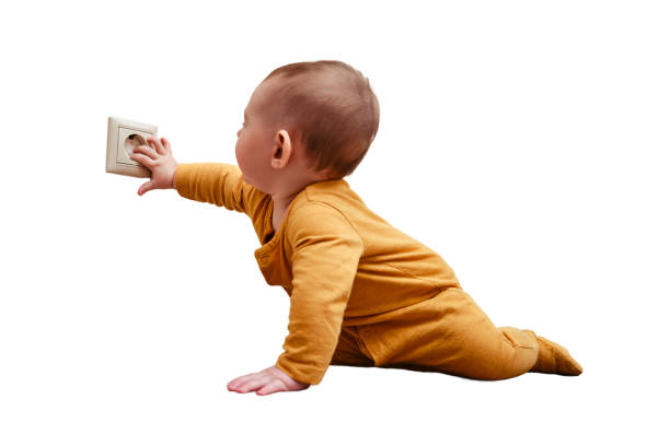 Baby toddler reaches into the electrical outlet on the home wall with his hand, isolated on a white background. Danger and protection of child fingers from electric shock Baby toddler reaches into the electrical outlet on the home wall with his hand, isolated on a white background. Danger and protection of child fingers from electric shock babyproof stock pictures, royalty-free photos & images