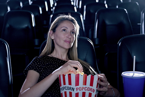 Woman alone at the cinema eating popcorn
