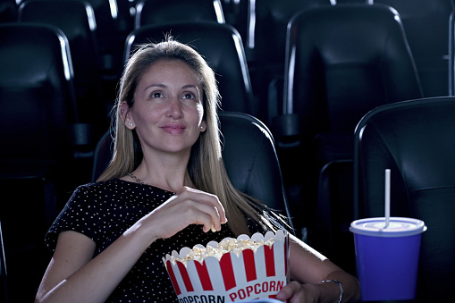 Woman alone at the cinema eating popcorn