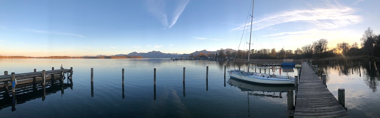 A panoramic shot of a dock and a boat at sunrise.