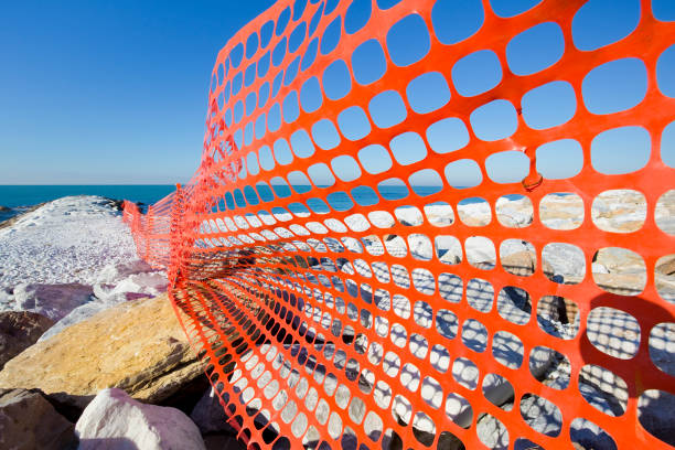 istock Perforated safety orange plastic grid to delimit a construction site areas by the sea 1449428708