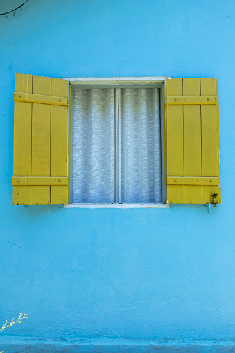 Decorative yellow window with white curtain on blue wall. Contryside of Sap Paulo state, Brazil