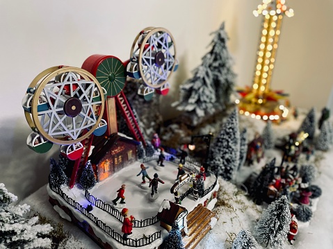 a christmas scene of a toy christmas fair, with a carousel with figurines in the foreground, other attractions in the background out of focus, recreation of a christmas fair with ceramic scale models