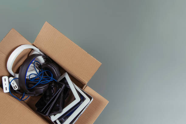 istock Cardboard box full of old used computers, digital tablets, smartphones, electronic gadgets for recycling on gray background. Donation, e-waste, electronic waste for reuse, refurbish, recycle concept 1449436837