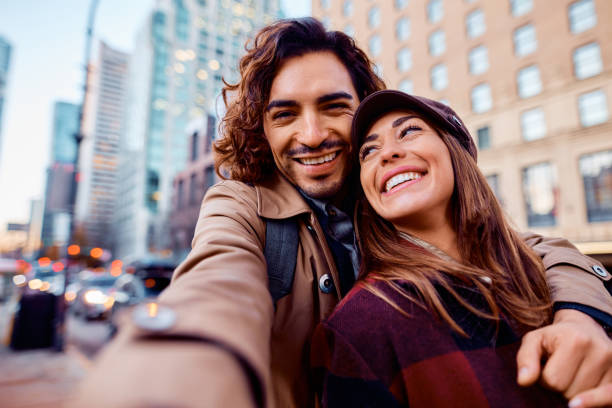 istock Young happy couple having fun while taking selfie in the city. 1449440610