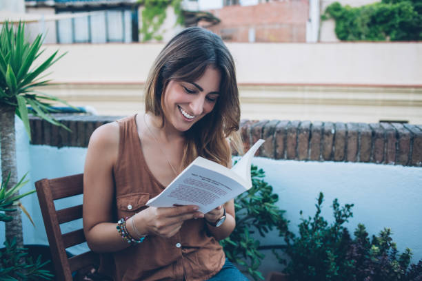 istock Gladful young woman reading book on balcony in daytime 1449441141