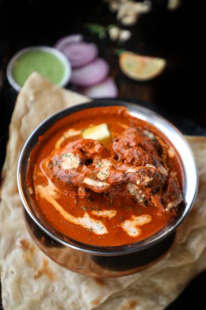 Butter chicken with naan Butter chicken with naan and salad in background on dark background fresh cilantro stock pictures, royalty-free photos & images