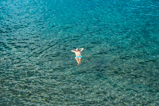 Dominica, Roseau - November 12 2022: Top view of a man floating in clear tropical water, enjoying summer vacation