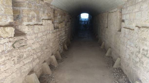 istock Tunnel path surrounded by stone walls leading to a light 1449457178
